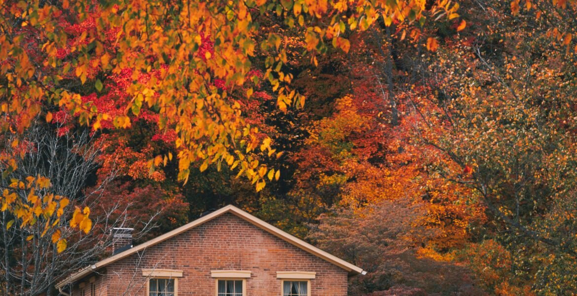 Brick house surrounded by colorful autumn foliage